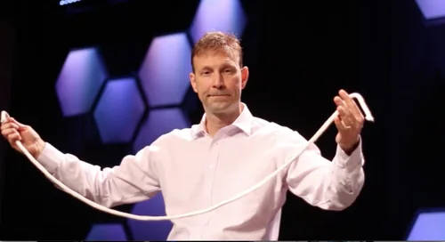 Bruce Eicher demonstrating a rope illusion onstage against purple lighting.